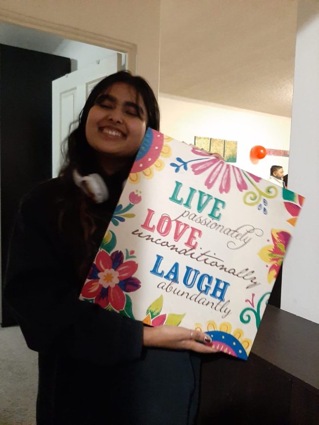 A picture of me! I'm smiling and holding a sign that says "LIVE passionately, LOVE unconditionally, LAUGH abundantly".
